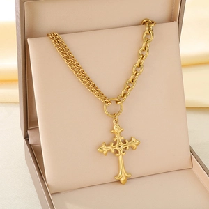 Vue détaillée d'un collier avec pendentif croix dorée sur soie dans un coffret