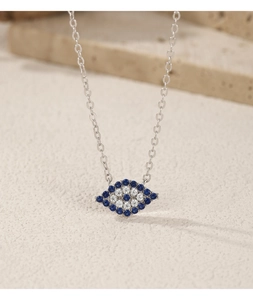 Macro shot of silver necklace with blue and white evil eye pendant on stone base