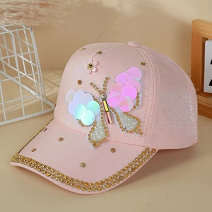 Détail de casquette rose avec papillon à paillettes et embellissements de perles
