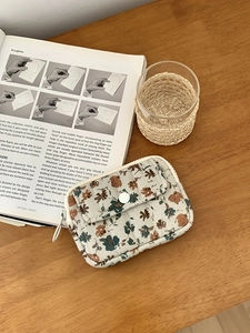 Quilted floral coin purse with snap button closure on a wooden desk with a notebook