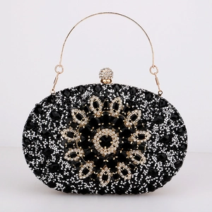 Detail of black rhinestone evening clutch with gold metal flower and gemstone inlay