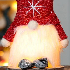 Macro shot of glowing Christmas gnome ornament with red sequin hat and plush white beard