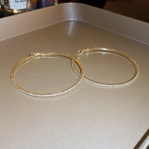 Macro shot of gold hoop earrings with pavé set crystals on a reflective metal tray