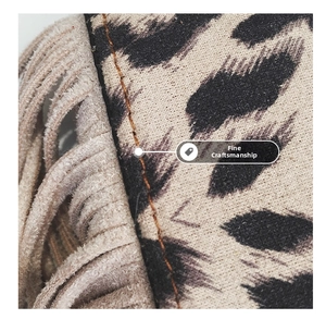 Close-up of leopard print fabric with beige suede tassels and orange stitching on child bag