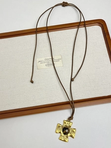 Detailed macro view of the golden cross pendant with heart-shaped tiger eye stone inlay
