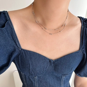 Close-up of double-layer stainless steel beaded chain necklace on model collarbone
