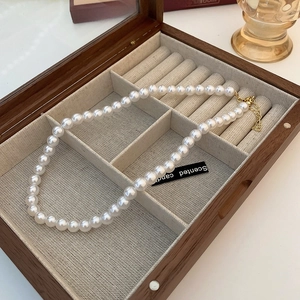 Detail of single strand pearl necklace with gold clasp in a wooden jewelry storage box
