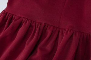 Detailed close-up of dark red knitted fabric featuring elegant ruched and pleated stitching