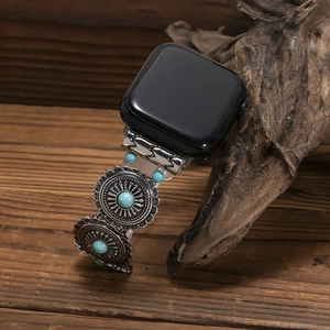 Detailed shot of silver metal watch band with turquoise charms on a rustic wood base