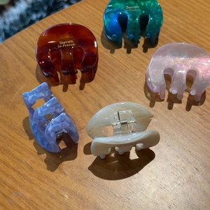 Macro shot of acetic acid hair claws in five colors with golden Barrette la France text