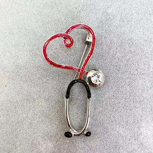 Macro view of stethoscope heart brooch with red enamel and sparkling crystal detail
