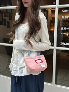 Dettaglio della trama trapuntata a cuore di una mini borsa rosa con tracolla in denim blu