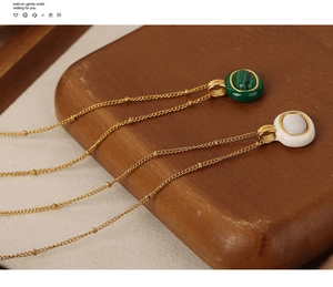 Detail of vintage gold plated necklaces featuring malachite and shell pendants on wood