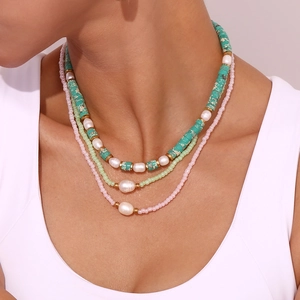 Detail of a three-layer necklace featuring turquoise beads and freshwater pearls on a model