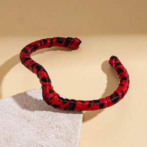 Detail of red and black woven leather cuff bracelet on minimalist stone background
