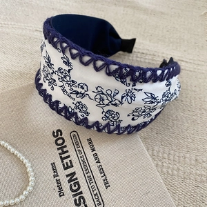 Detailed macro view of retro floral print wide headband with blue crochet lace trim edges