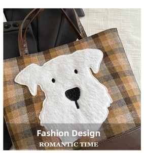 Detail of vintage plaid tote bag featuring a white plush dog patch and leather handles