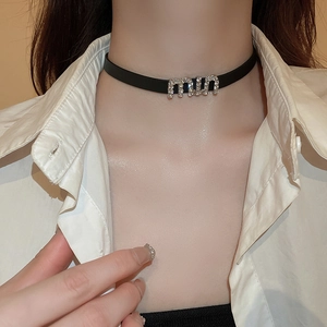 Detailed view of black faux leather choker featuring sparkling rhinestone miu letter charm