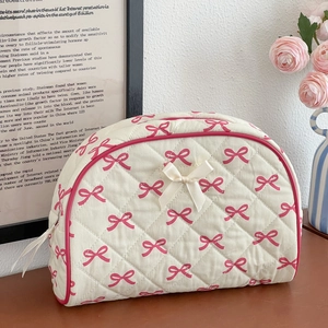 Close-up of quilted bow makeup bag with pink floral print on a wooden desk scenery