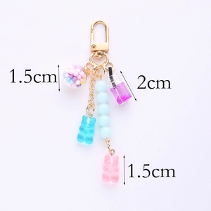 Detail of cute bear charms and colorful beads on a gold keychain for earphone cases