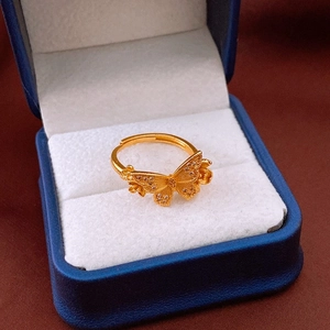 Détail macro d'une bague papillon plaquée or avec zircons étincelants sur un coffret bleu