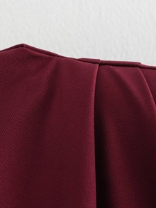 Détail macro des plis d'épaule bordeaux sur un haut sans manches avec coutures fines