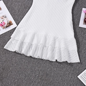 Détail d'une robe blanche avec tissu texturé et ourlet à volants sur fond sombre
