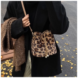 Detail of leopard print faux fur bucket bag with chain drawstring and pearl accents
