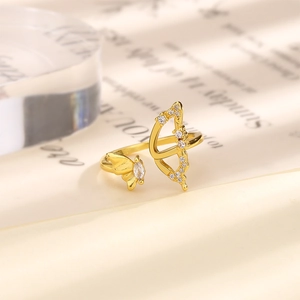 Detailed close-up of golden bow and arrow open ring with sparkling cubic zirconia crystals
