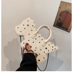 Detail of creative dinosaur shape beige handbag featuring black rivets and metal chain strap