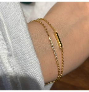 Detail view of double-layer gold bracelets with pavé diamonds on model's wrist