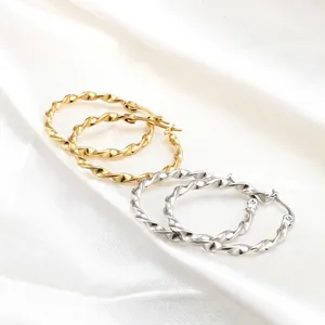 Minimalist twisted rope hoop earrings in polished gold and silver finishes on silk