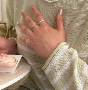 Detail of twisted and minimalist 925 sterling silver knotted rings worn on a hand
