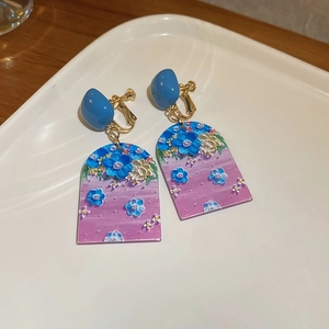 Macro detail of asymmetric heart clip-on earrings with oil-painted floral arch design