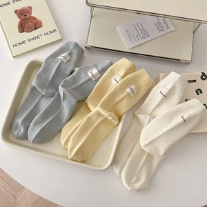 Set of three ribbed cotton mid-calf socks in grey-blue, pale yellow, and cream with labels