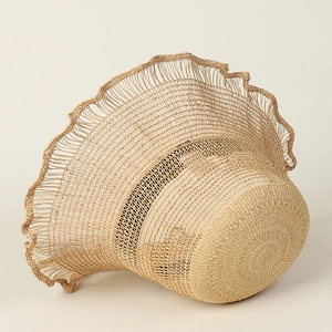 Macro detail of natural raffia straw sun hat with wavy brim and intricate weave texture