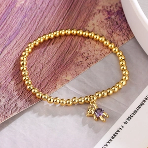 Golden beaded bracelet featuring a cute bear pendant with a vibrant purple zircon stone