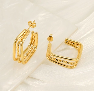 Close-up of golden multi-layer rectangular stud earrings with a refined twisted metal texture