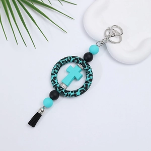 Detail of DIY silicone car charm with leopard print ring, teal cross, and black tassel