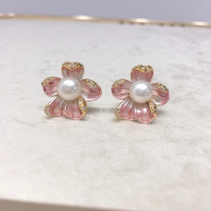 Macro shot of 18K gold floral stud earrings with pink petals, pearl and pavé crystals