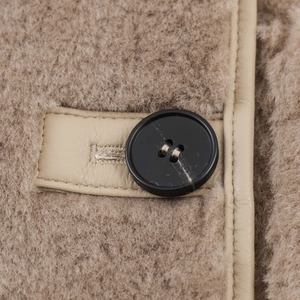 Close-up of khaki faux shearling fabric with leather trim and black button detail