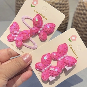 Set of bright pink sequin butterfly hair clips with faux pearls on display card