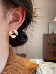 Detail of 14K gold plated flower earrings with crystal edges on a model's ear