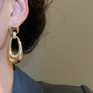 Detail of gold-plated oval drop earring featuring cubic zirconia accents and sleek metal finish
