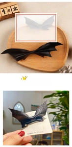 Detail of black bat wing hair clip showing litchi leather texture and back clip design