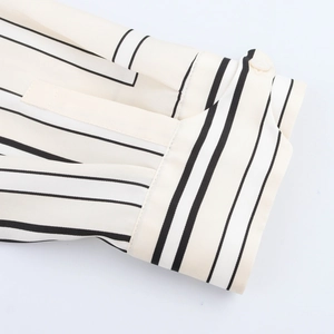 Close-up of white satin shirt cuff with black stripes and a single button detail