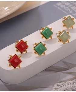 Close-up of geometric square titanium earrings with red and green natural stones