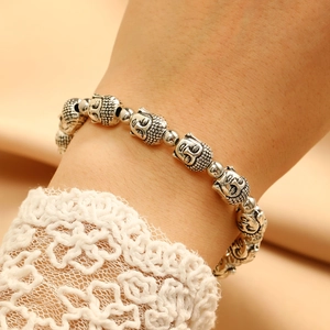 Detailed close-up of a silver Buddha head beaded bracelet with vintage carved textures