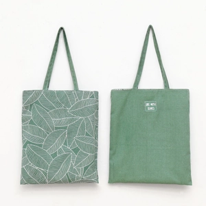 Detail of forest green canvas tote bag showing leaf prints and solid color texture