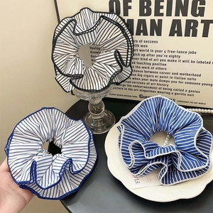 Three elegant blue and white striped fabric scrunchies displayed in a retro aesthetic layout